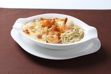 oven baked creamy cheese carbonara cream sauce pasta noodle with fresh big prawn seafood chicken chop in bowl on brown cloth white background design western chef cuisine halal food menu for cafe