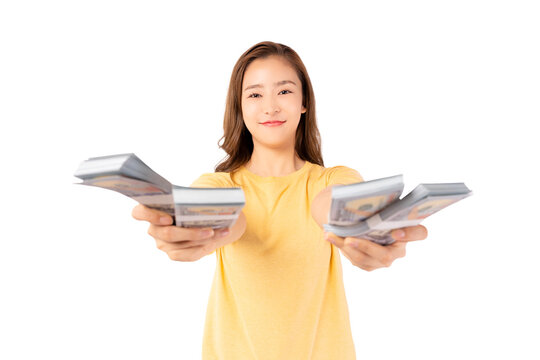 Happy young asian woman holding money banknotes and celebrating isolated over yellow background Happy asian lady showing money dollars and Smiling satisfied girl earning a lot of money She give money