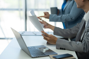 senior asian business woman Discuss and advise Consulting young office workers about marketing plans, paperwork, financial information from the tablet to analyze and summarize the work in the office
