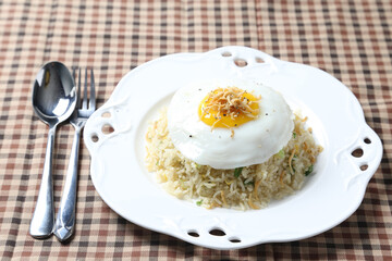 wok fried garlic olive egg rice with small silver fish seafood, fried egg and vegetables in plate on vintage table cloth white background asian chef cuisine halal food menu for cafe