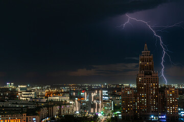 Fototapeta premium Astana, Kazakhstan, August, 2023. Night view of the skyscraper of the central street of the capital during a thunderstorm with lightning.