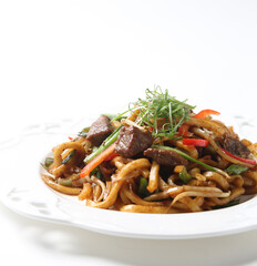stir fried Japanese udon noodle mee in black pepper sauce with wagyu beef slices meat in plate chopstick on brown cloth white table asian chef cuisine halal food menu for restaurant