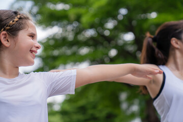 A happy girl exercising training in yoga and looking at the female instructor next to her in the park ,text space