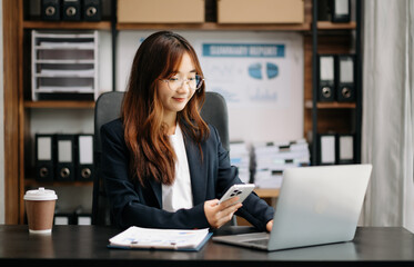 Fototapeta na wymiar Confident Asian woman with a smile standing holding notepad and tablet at the modern office.