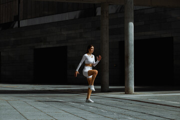 Sporty girl performs functional training on the street.