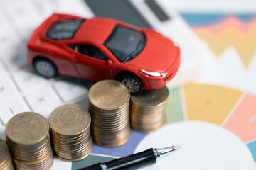 Miniature car model and Financial statement with coins. Finance and car loan, saving money for a car concepts. Car loan, money, banknote on agreement document or car insurance application form.