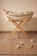 woven moses basket against a cream background on a wooden stand, blankets inside
