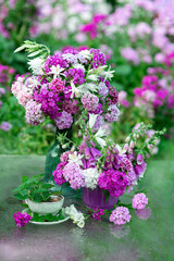 Pink flowers in a vase and mint tea on a natural background in the garden