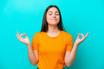 Young caucasian woman isolated on blue background in zen pose