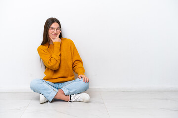 Young girl sitting on the floor isolated on white background smiling