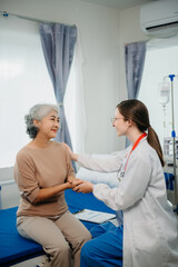 Obraz premium Doctor in white suit take notes while discussing and Asian elderly, woman patient who lying on bed with receiving saline solution in hospital or clinic.