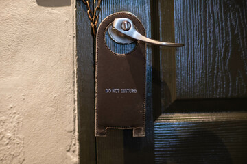 Closed hotel room door with a sign please do not disturb.