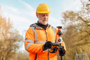 Site engineer operating his touch screen controller instrument during roadworks. Builder using...