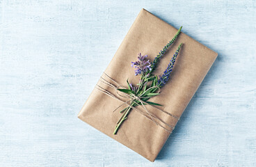 Book wrapped as a gift with purple flowers. Top view. Copy space