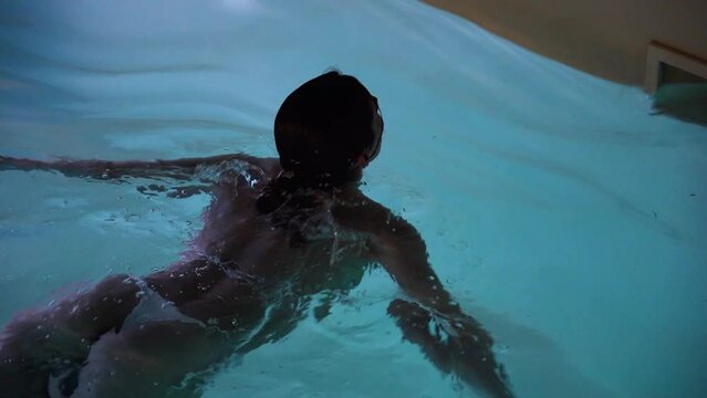 Attractive female model in white swimsuit lying in poolside water at hotel, tourism concept. Portrait of beautiful woman in swimwear relaxing in swimming pool 