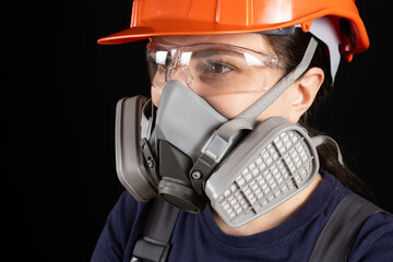 A woman wearing a helmet, respirator and goggles on a black background - obrazy, fototapety, plakaty
