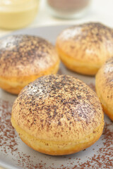 Donat tiramisu, sweet donuts with a variant of Tiramisu topping, served on a plate with a white background