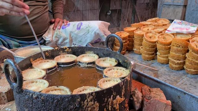Indian sweet maker making ghewar traditional fried dish dipped in syrup and covered with rabri condensed milk served in rajasthan, punjab and delhi