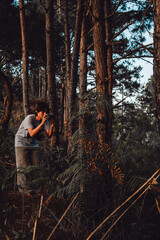 Cheerful female photographer stands with a car on the side of the road taking a picture with a digital camera in the mountains. Travel and active living and tourism concept.