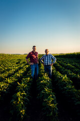 Fototapeta na wymiar Portrait of two farmers standing in soy field looking at camera.