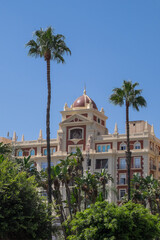 Fototapeta na wymiar Palmeras y antiguo edificio modernista en la avenida marítima de la ciudad de Málaga, España