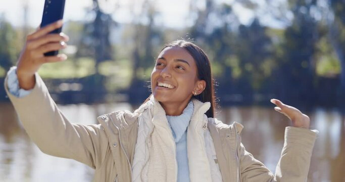 Camping, video call and Indian woman in a at a lake for selfie, view or profile picture in a forest. Social media, female and travel influencer live streaming in nature for blog or podcast update