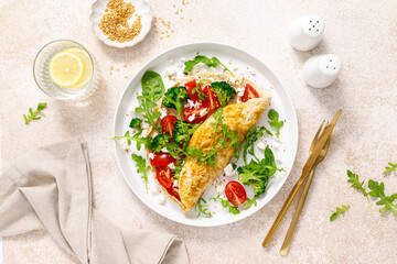 Omelette stuffed with tomato, broccoli feta cheese and fresh green salad. Healthy diet food for breakfast. Top view