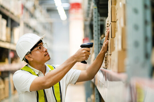 Male warehouse worker scanning barcodes on boxes in a warehouse. Male warehouse worker working with barcode scanner.