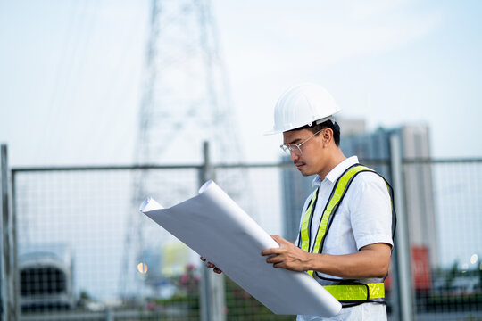 Engineer holding blueprints at construction site. Planning and working on the construction and design of buildings.