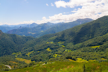 Fototapeta na wymiar Tall Mountains, White Clouds, and Green Meadow: Beautiful Scenic View
