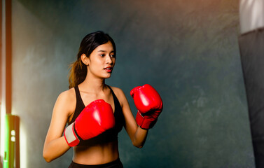 Sports boxing. Boxing. Asian woman wearing red gloves exercising with self-defense combat training. Training boxing. Muay Thai. Strike martial arts.