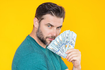 Man holding cash money in dollar banknotes on isolated yellow background. Studio portrait of...
