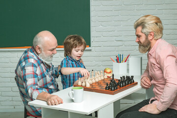 Grandfather father and son playing chess, men in different ages ready to study. Happy family in class at school. Three men generation. Senior teacher.
