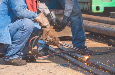 Cropped image of 2 welders are welding galvanized steel pipes with acetylene gas welding torch machine in construction site