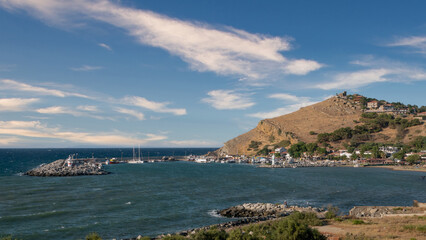 Kalekoy harbor on a windy day, moored boats and Kalekoy castle on the high mountain in the background. Gokceada, Canakkale, Turkey
