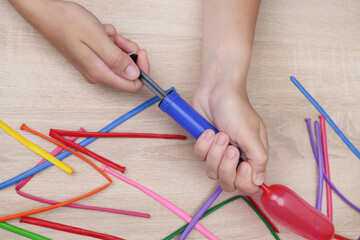 hands holding an air pump, inflate a balloon for making crafts, toys