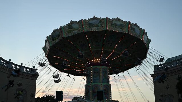 People are enjoying in the Amusement park with family members and rides during the summer evening.