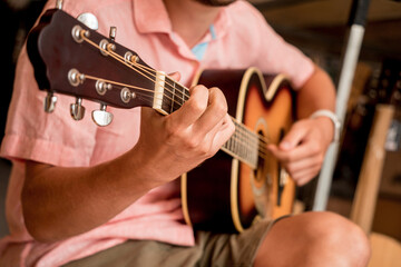 Young musician testing classical guitar in a guitar shop