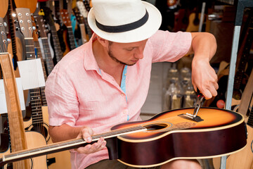 Young musician changing strings on a classical guitar in a guitar shop