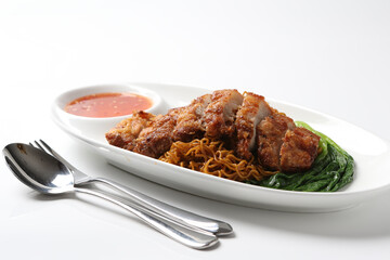 local wanton noodle mee in dark soy sauce with chicken chop cutlet, vegetables and chilli sauce in plate chopstick on white vintage newspaper background asian chef halal food restaurant banquet menu