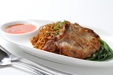 dry wanton noodle mee with grilled chicken pork cutlet and vegetable in dark soy and chilli sauce on plate chopstick on white vintage newspaper background asian chef halal food restaurant banquet menu
