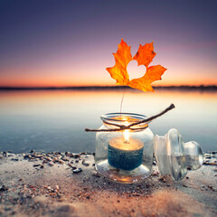 Kerze im Glas am Strand im Herbst