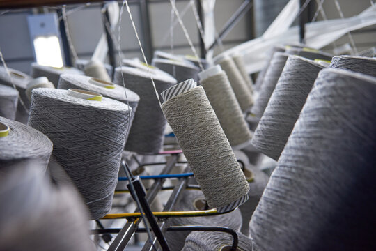 Raw spindles of industrial cotton in a weaving factory, hand weaving cotton for the fashion and textiles industry. Yarn weave traditional textile fabric manufacturing for clothing and fashion.