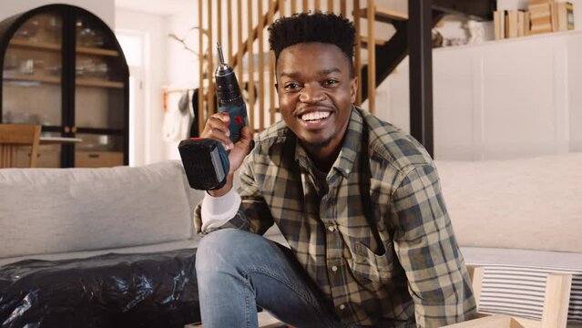 A Black Man Using an Electric Screwdriver To Build a Table in the Lounge