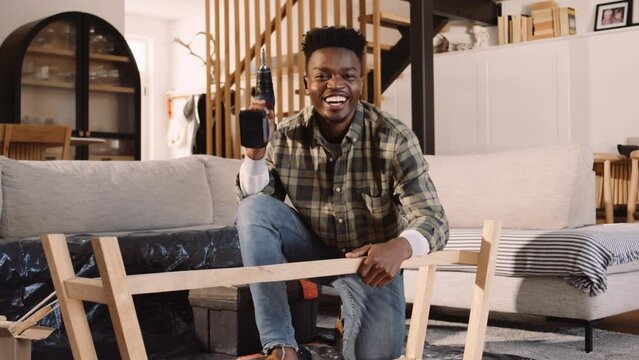 A Black Man Using an Electric Screwdriver To Build a Table in the Lounge