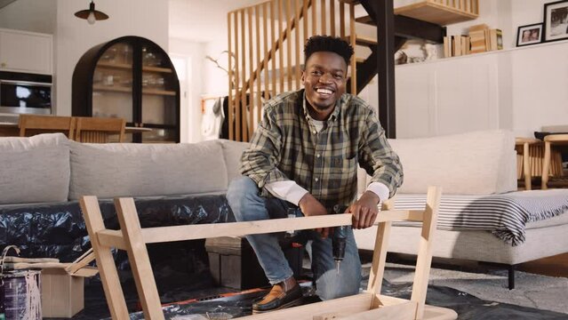 A Black Man Building a Wooden table in the Lounge