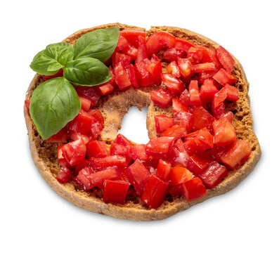 Italian dry bread friselle with chopped cherry tomatoes and basil leaves dressed with olive oil poured from oil bottle - isolated