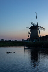 Beautiful wooden windmills at sunset in the Dutch village of Kinderdijk. Windmills run on the wind. The beautiful Dutch canals are filled with water. Beautiful sunset. - 634332563