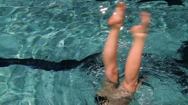 Synchronized swimmer during training on the pool upside down