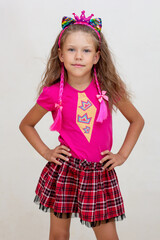 Caucasian little girl of 7 years with crown on head in pink cloth dressed in barbie style on white background